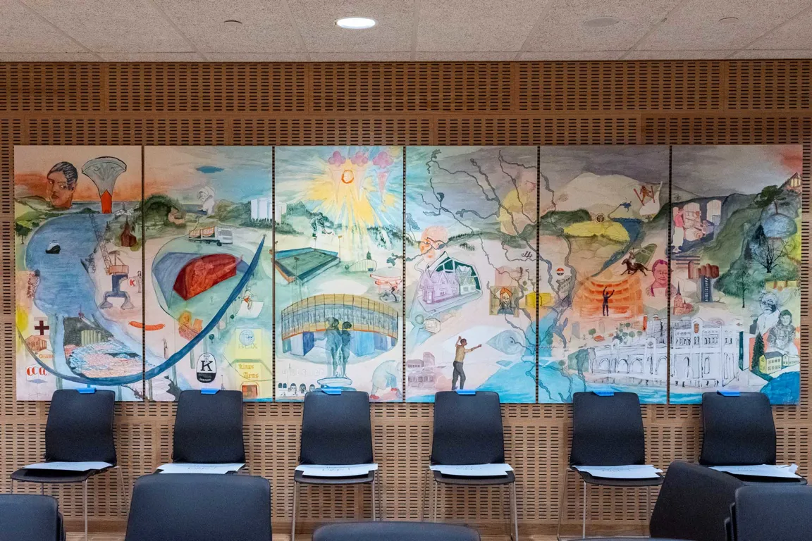 Et rom med stoler og en vegg med kunst på