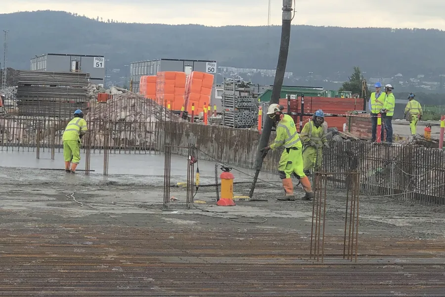 Mann fyller på betong for å støpe grunnplate.