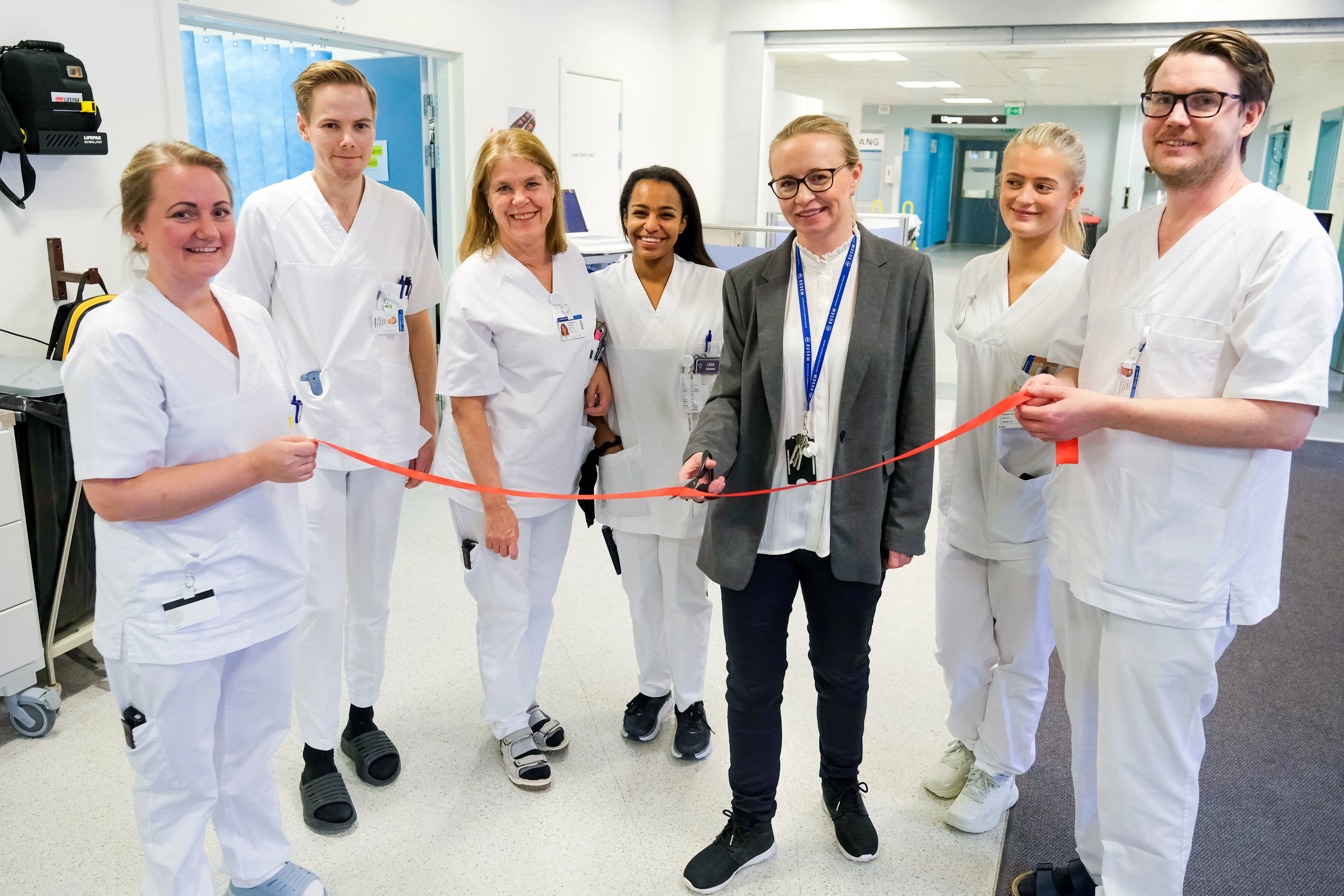 ​​Ansatte i akuttmottaket på Bærum sykehus klipper sin egen åpningsbånd - saksen blir håndtert av seksjonsoverlege Therese Valeb