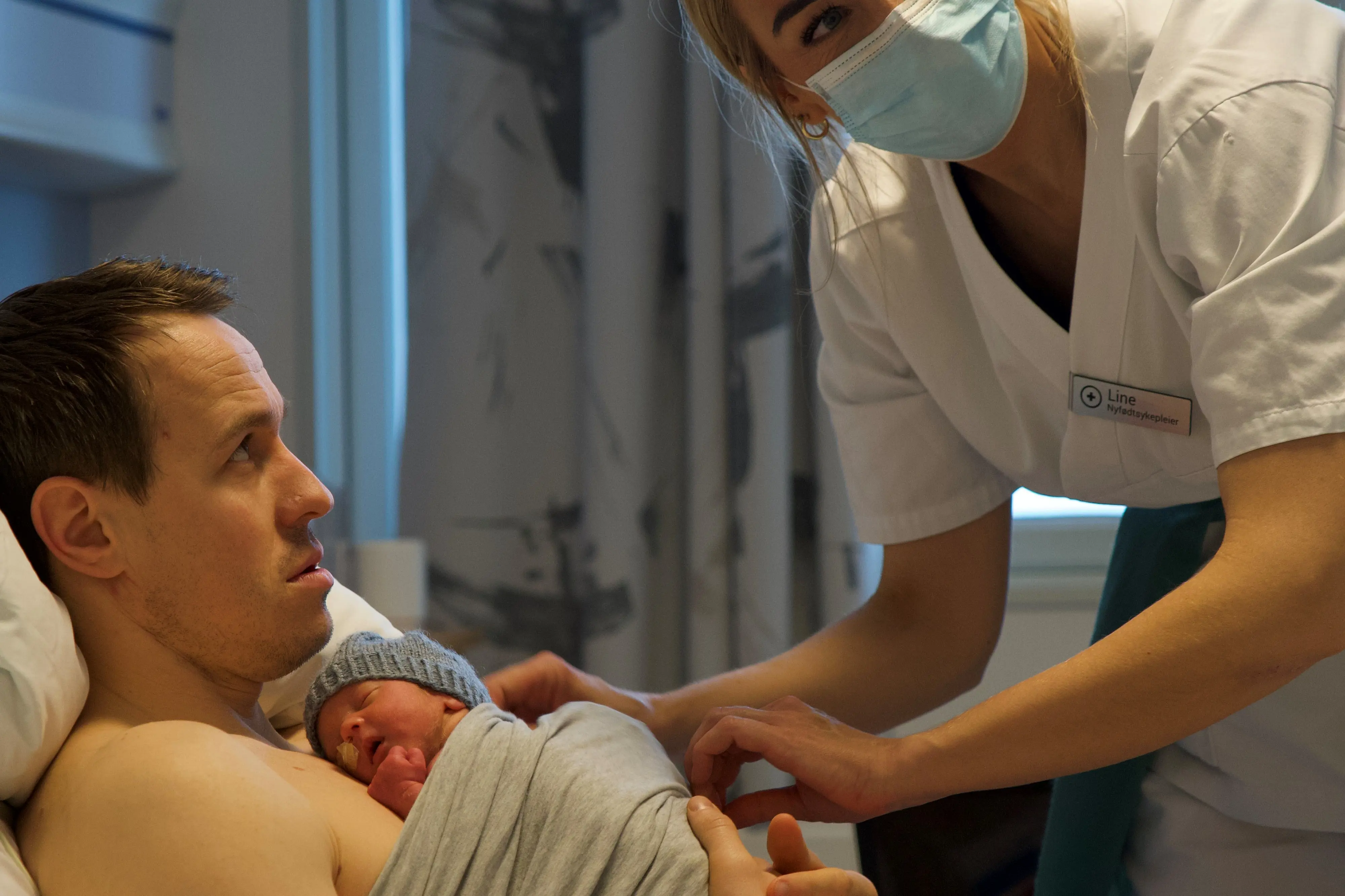 Nyfødtsykepleier Line sørger for hjelp med stell av Isac på pappa Jacob Kristiansens fang.