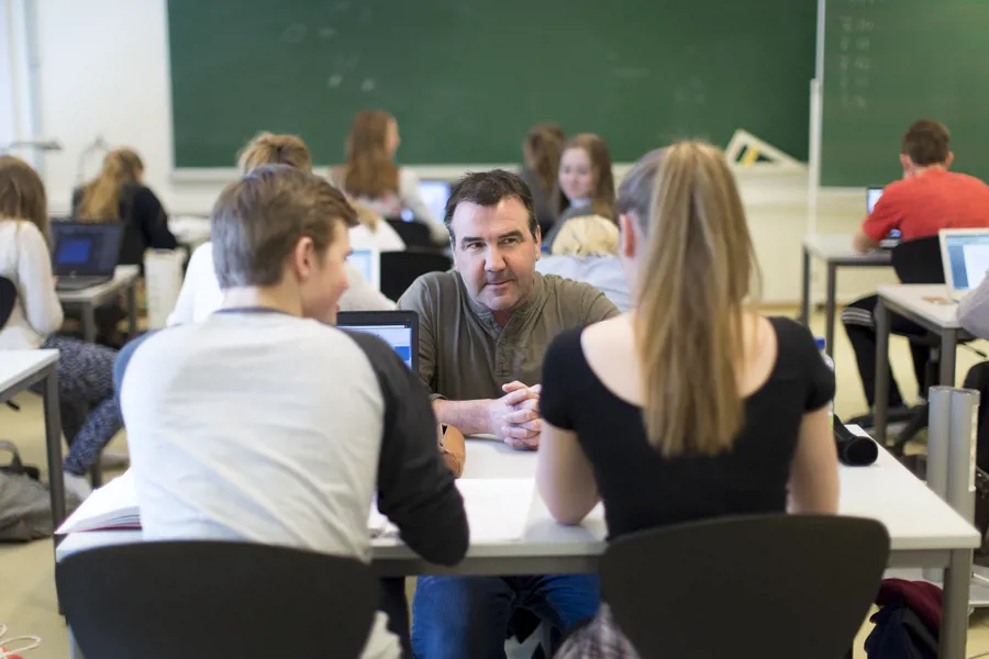 Mannlig lærer snakker med to elever