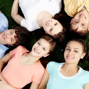 En gruppe mennesker som ligger på bakken og smiler til kameraet