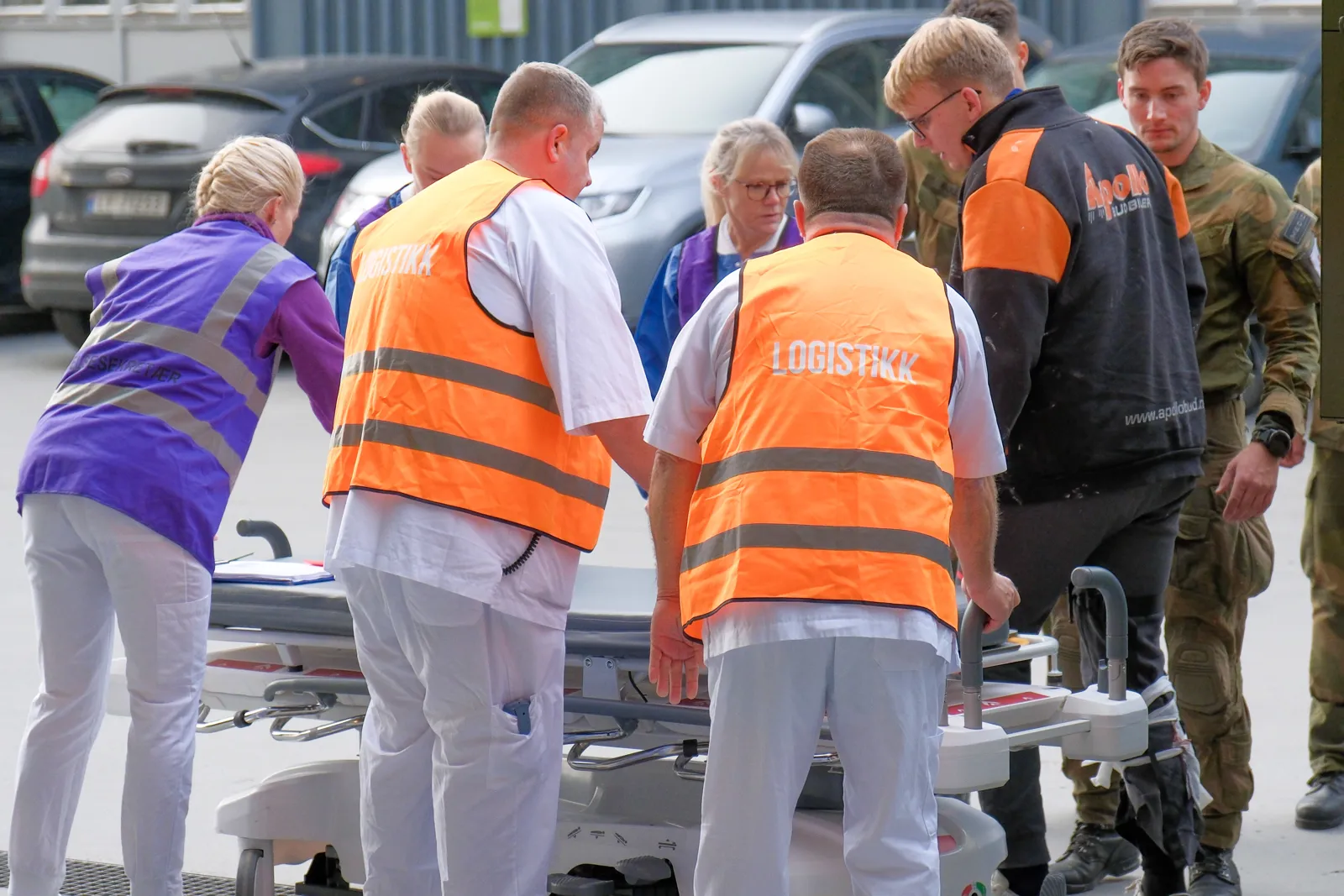 En gruppe mennesker som står rundt en mann i en oransje vest